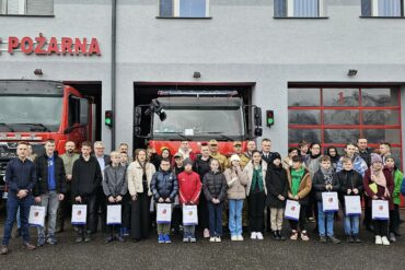 Pamiątkowe zdjęcie uczestników konkursu na tle samochodów ratowniczo-gaśniczych.